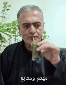 a man drinking from a glass with a straw and arabic writing on the bottom