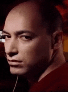 a close up of a man 's face with a red shirt on looking at the camera .