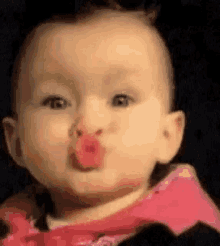 a baby is blowing a kiss with a pink lipstick on her lips .