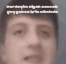 a blurry picture of a man 's face with the words kardesim siyah sancak written above it