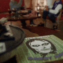 a book with a picture of a woman on the cover is sitting on a table with a record player in the background