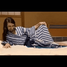 a man with long hair and a beard is laying on a bed .