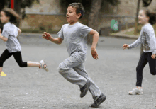 a boy in a grey shirt is running with two girls