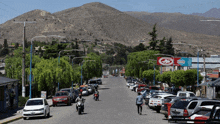 a row of cars are parked on the side of a road with a red sign that says ' coca-cola ' on it