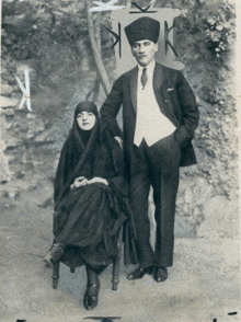 a man in a suit and tie stands next to a woman in a black dress