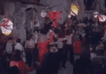 a blurry picture of a crowd of people dancing in a room with lanterns hanging from the ceiling .