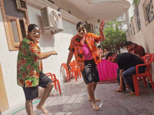 two men wearing masks are dancing in front of an air conditioner that says mitsubishi