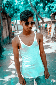 a young man wearing sunglasses and a white tank top poses for a photo