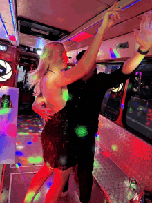 a woman in a black dress is dancing with a man in a black shirt in front of a sign that says happy