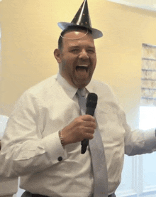 a man with a party hat on his head holds a microphone