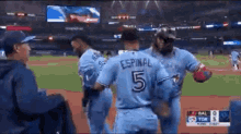 a group of baseball players are standing on a field and one of them is wearing a number 5 jersey .