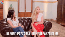 two women are sitting on a couch and the words io sono pazza ma lui e più pazzo di me are above them