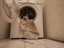 a white washing machine with the door open and a dirty bag in it