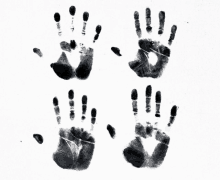 four black hand prints on a white background with the middle one being the largest