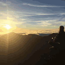 a person sitting on top of a mountain watching the sun set