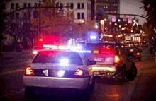 a police car is driving down a street at night .