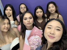 a group of women posing for a picture with one holding a pink bouquet of flowers