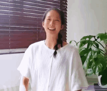 a young woman in a white shirt is smiling in front of a window .