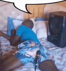 a man in blue shorts is laying on a bed with a speaker in the background