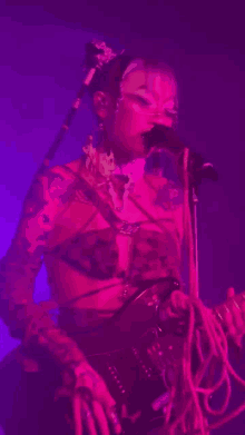 a woman is singing into a microphone while playing a guitar in a purple light .