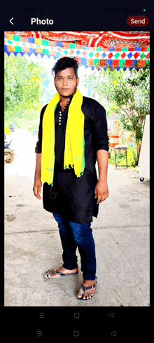 a man with a yellow scarf around his neck is standing in front of a sign that says send