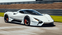 a white supercar is driving on a track