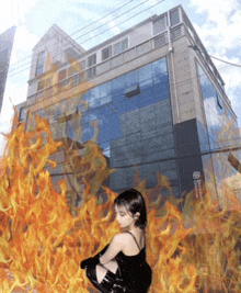 a woman in a black dress is surrounded by flames in front of a building that says ' toronto ' on it