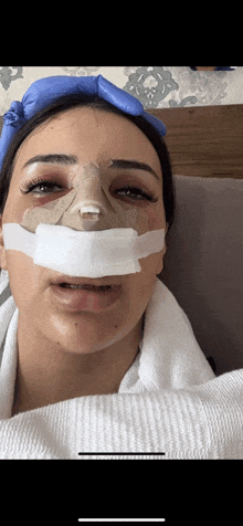 a woman in a hospital bed with a bandage on her nose