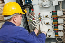 a man wearing a yellow hard hat is working on a electrical box