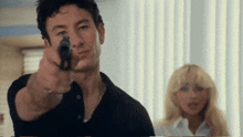 a man is pointing a gun at a blonde woman