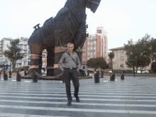 a man stands in front of a statue of a horse in a city