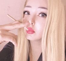 a woman with blonde hair is smoking a cigarette and making a peace sign