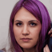 a woman with purple hair is looking at the camera