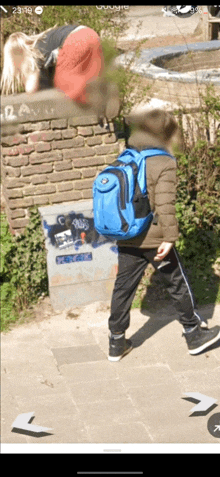 a boy with a blue backpack walking down a sidewalk