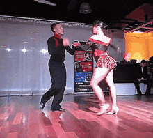 a man and a woman are dancing on a dance floor in front of a sign that says ' tango ' on it