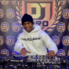 a man wearing a total full sound hoodie stands in front of a dj pro banner