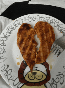 a plate with a chicken breast in the shape of a heart with graffiti around it