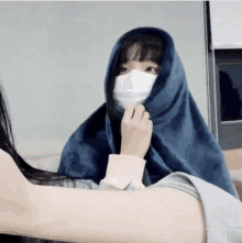 a girl wearing a mask is wrapped in a blue blanket