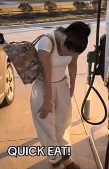 a woman is standing in front of a gas pump at a gas station with a bag on her back .