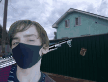 a man wearing a black mask holds a gun in front of a house