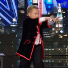 a young boy in a black and red suit performs a trick on a stage in front of a screen that says spain talent