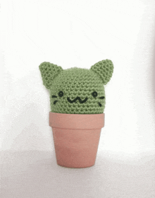 a knitted green cactus with cat ears and a cat face