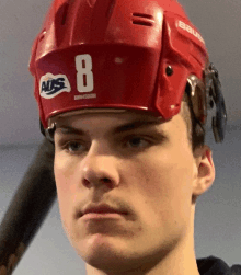 a young man wearing a red hockey helmet with the number 8 on it