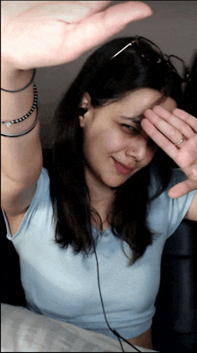 a woman covering her face with her hand while wearing ear buds