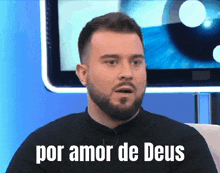 a man with a beard says por amor de deus in front of a television screen