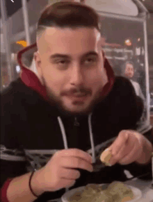 a man with a beard is eating a plate of food .