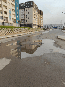 a reflection of a building in a puddle of water on a street