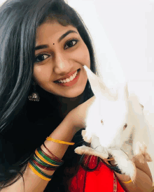 a woman holds a white rabbit in her hands and smiles