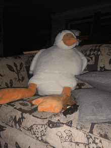 a stuffed duck is sitting on a couch with a floral pattern