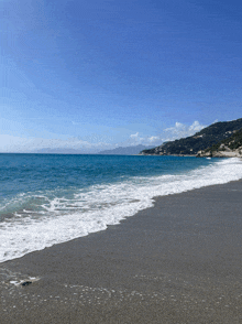 waves crashing on a sandy beach with mountains in the distance